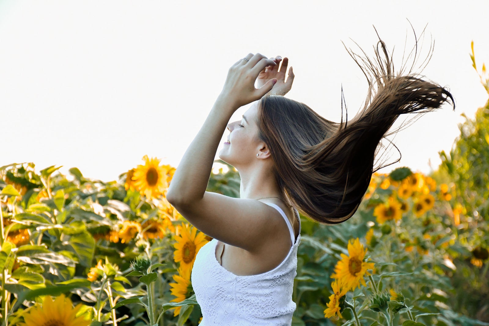 woman in white tank top standing on yellow flower field during daytime